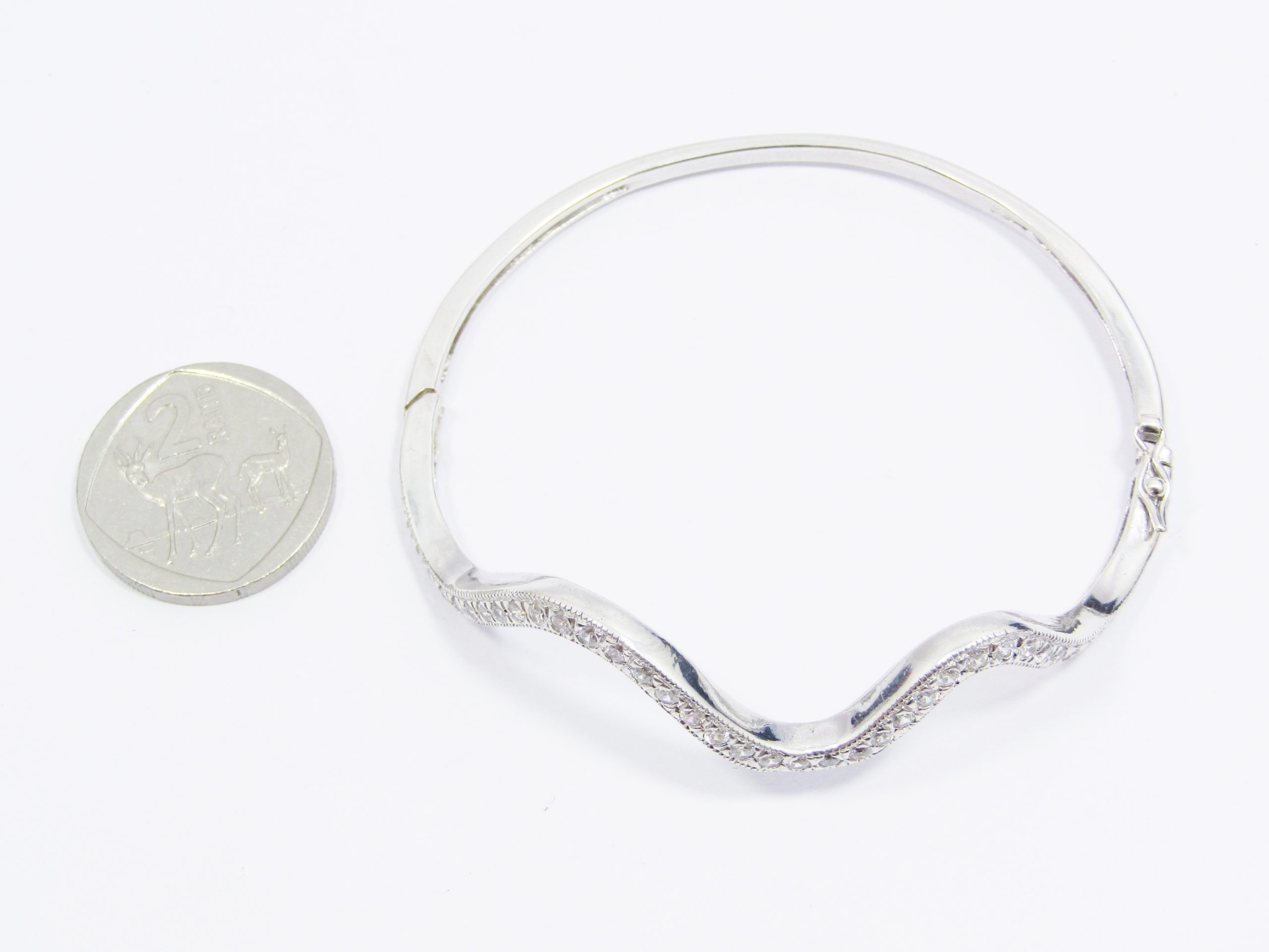 A Lovel Swirl Design Zirconia Hinged Bangle in Sterling Silver.