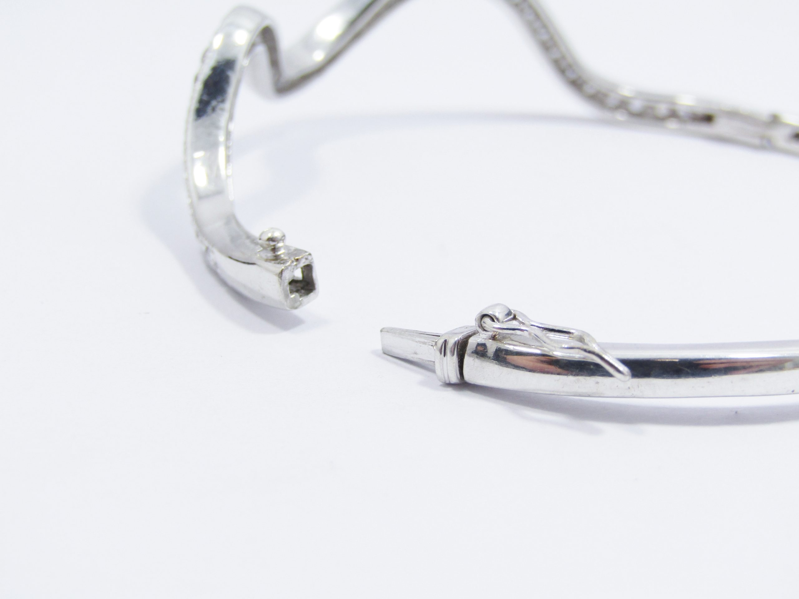 A Lovel Swirl Design Zirconia Hinged Bangle in Sterling Silver.