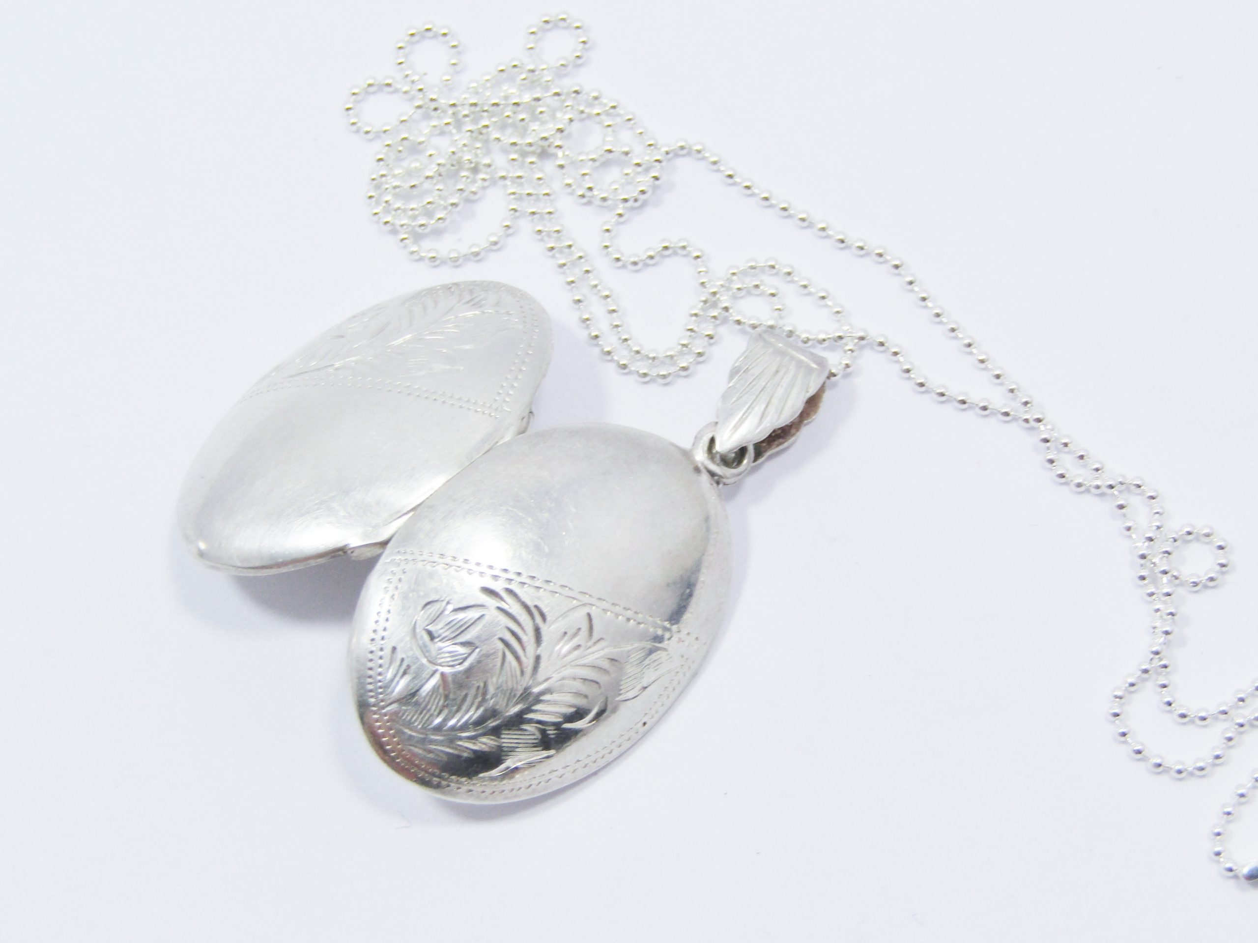 A Lovely Oval Vintage Design Engraved Locket on Chain in Sterling Silver.